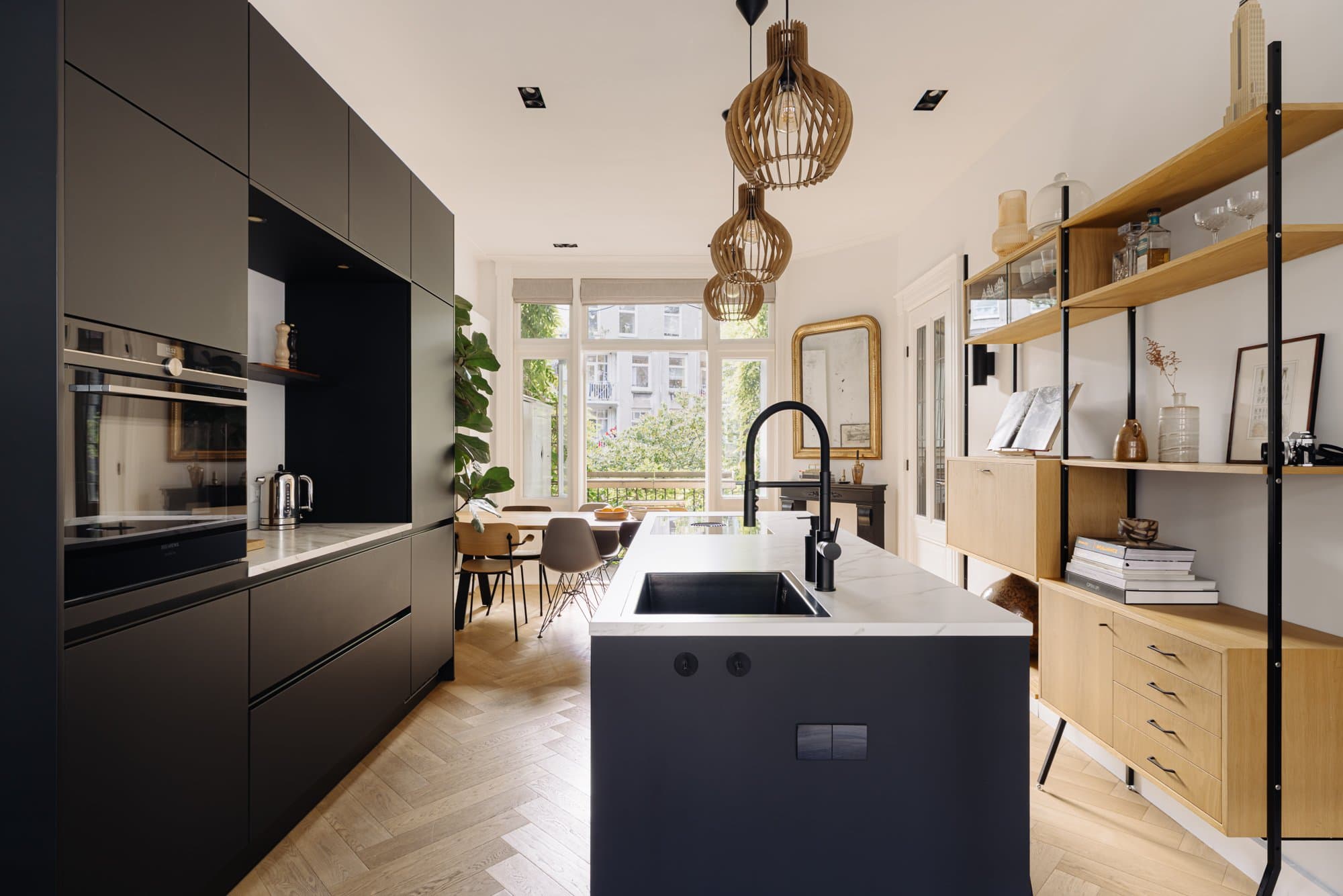 Zicht door de keuken langs het eiland naar de eettafel bij het raam