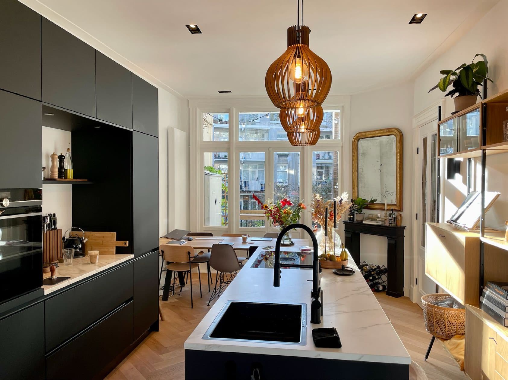 Nieuwe zwarte keuken met kookeiland, visgraatvloer en pendelverlichting