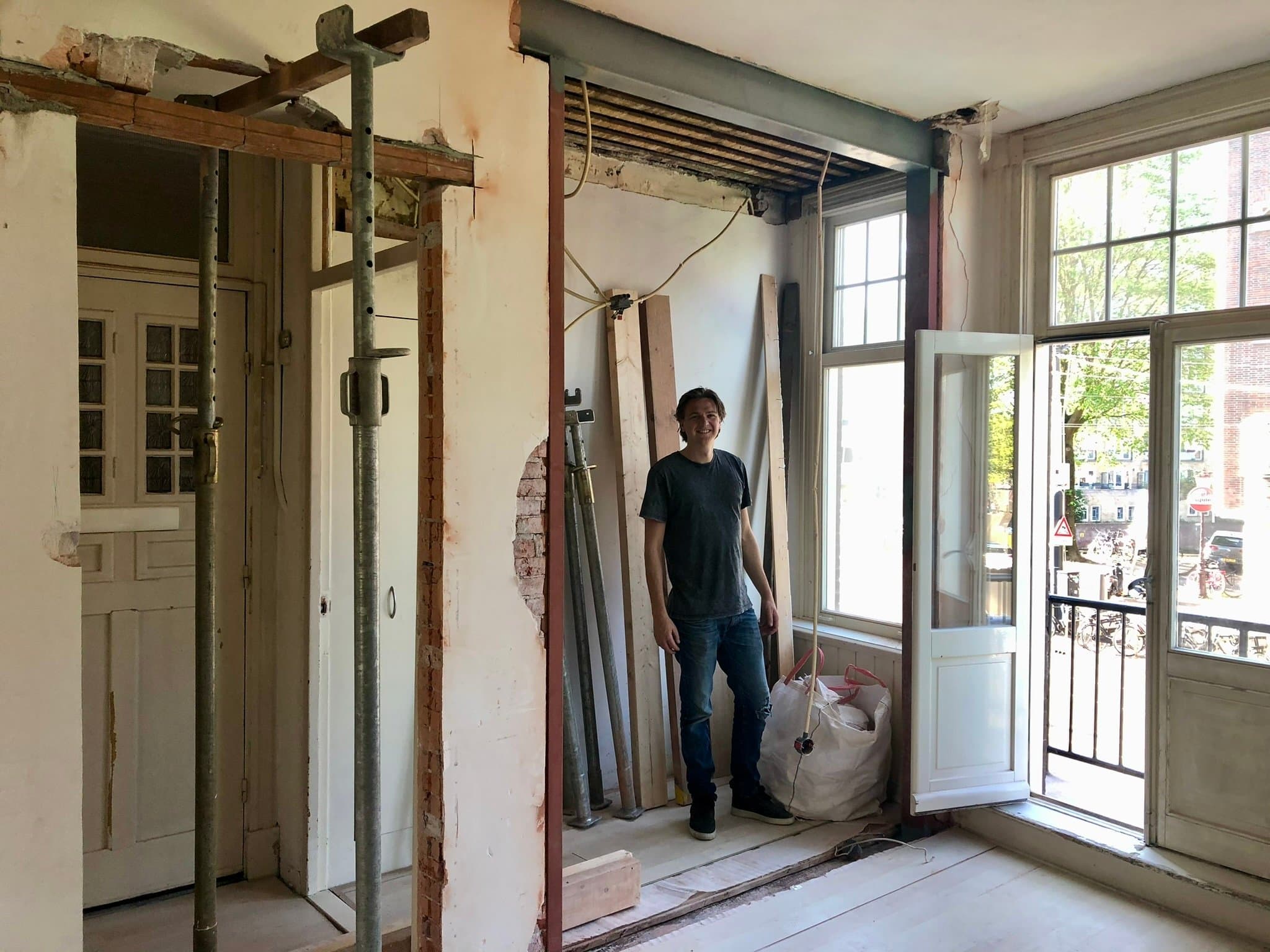 De woning in gestript casco tijdens de verbouwing, met stutten en opgestapelde deuren bij het balkon