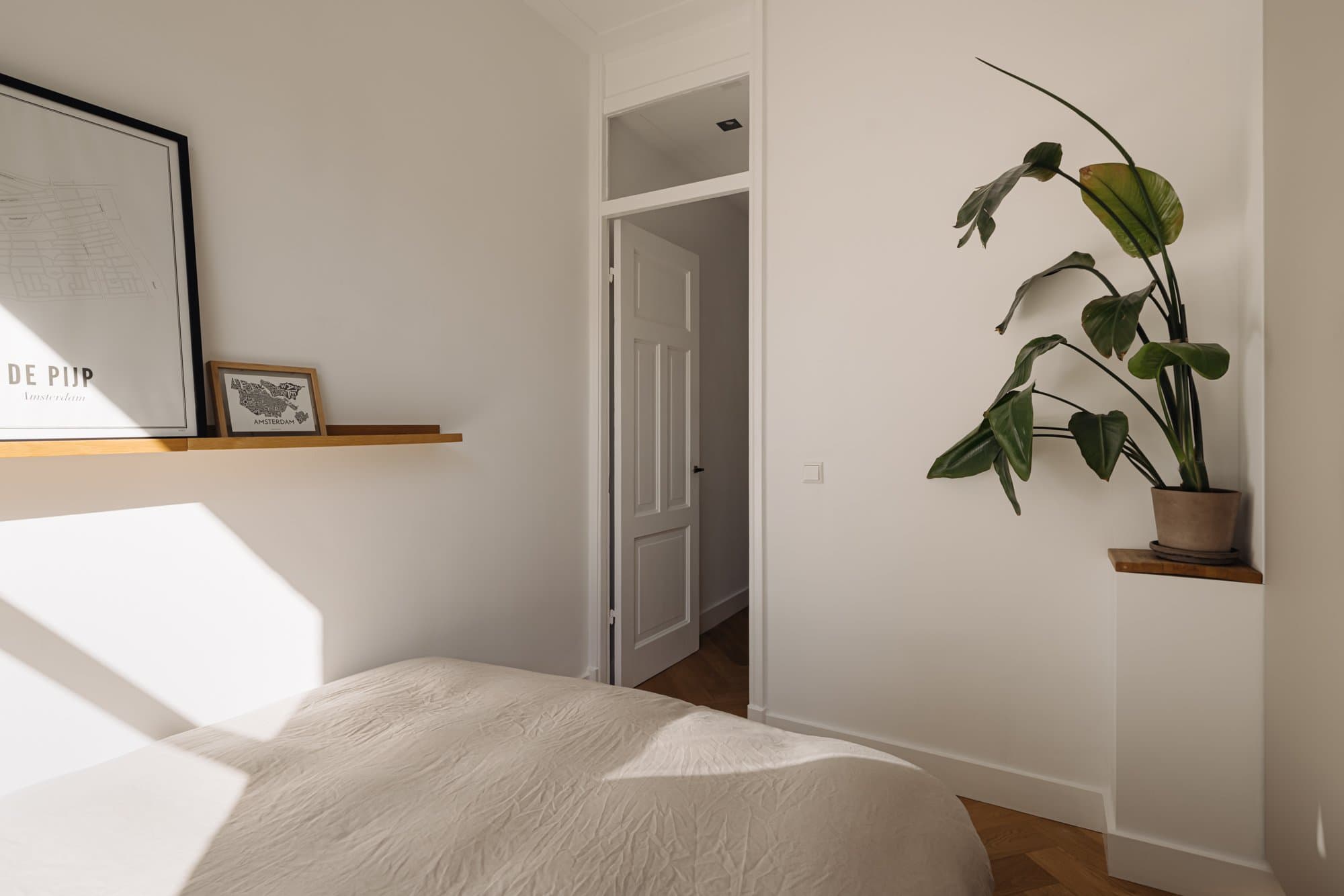 De slaapkamer met bed, planken en planten bij de deuropening