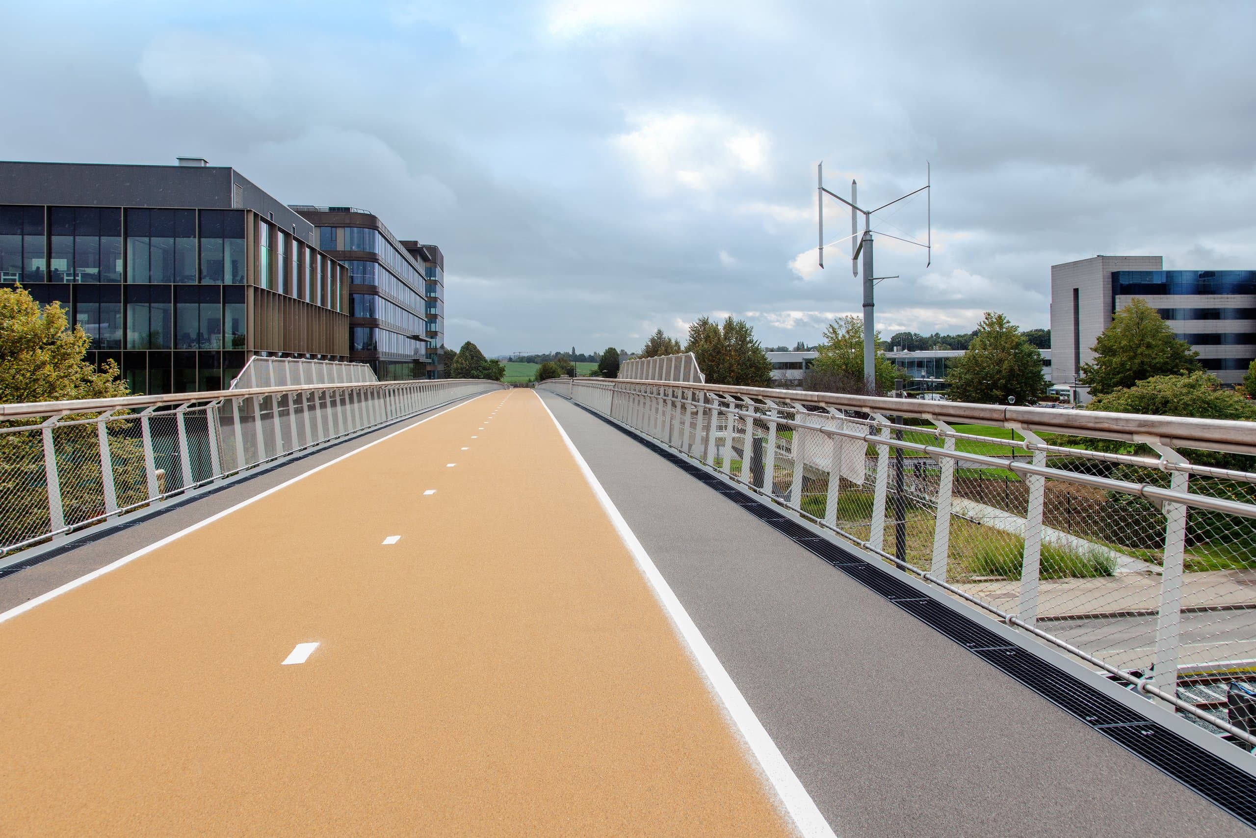 Op het brugdek van de gerealiseerde fietsbrug: het gele fietspad richting de kantoren