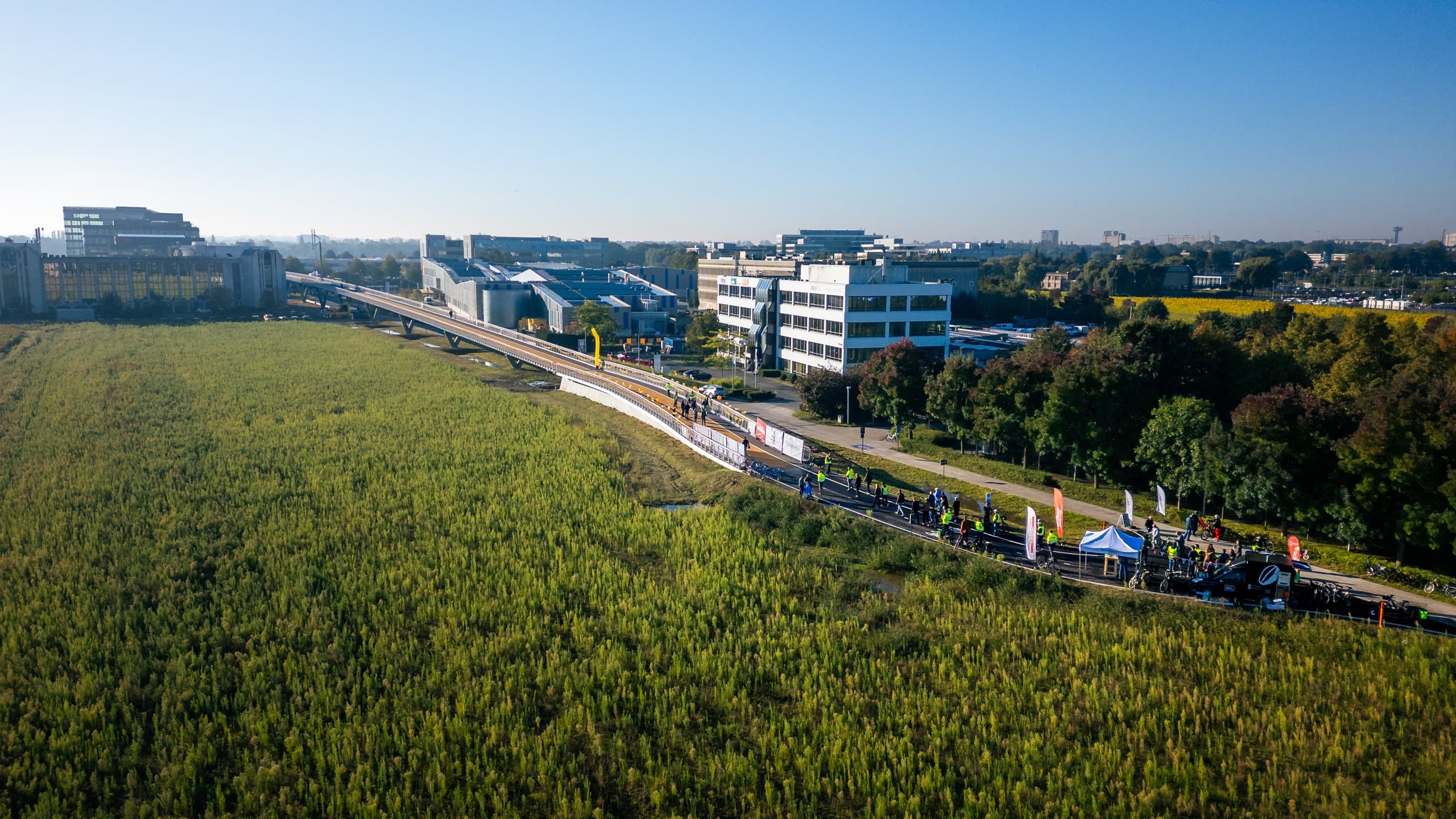 Feestelijke opening van de fietsbrug, met publiek en fietsers tussen de bloemenvelden