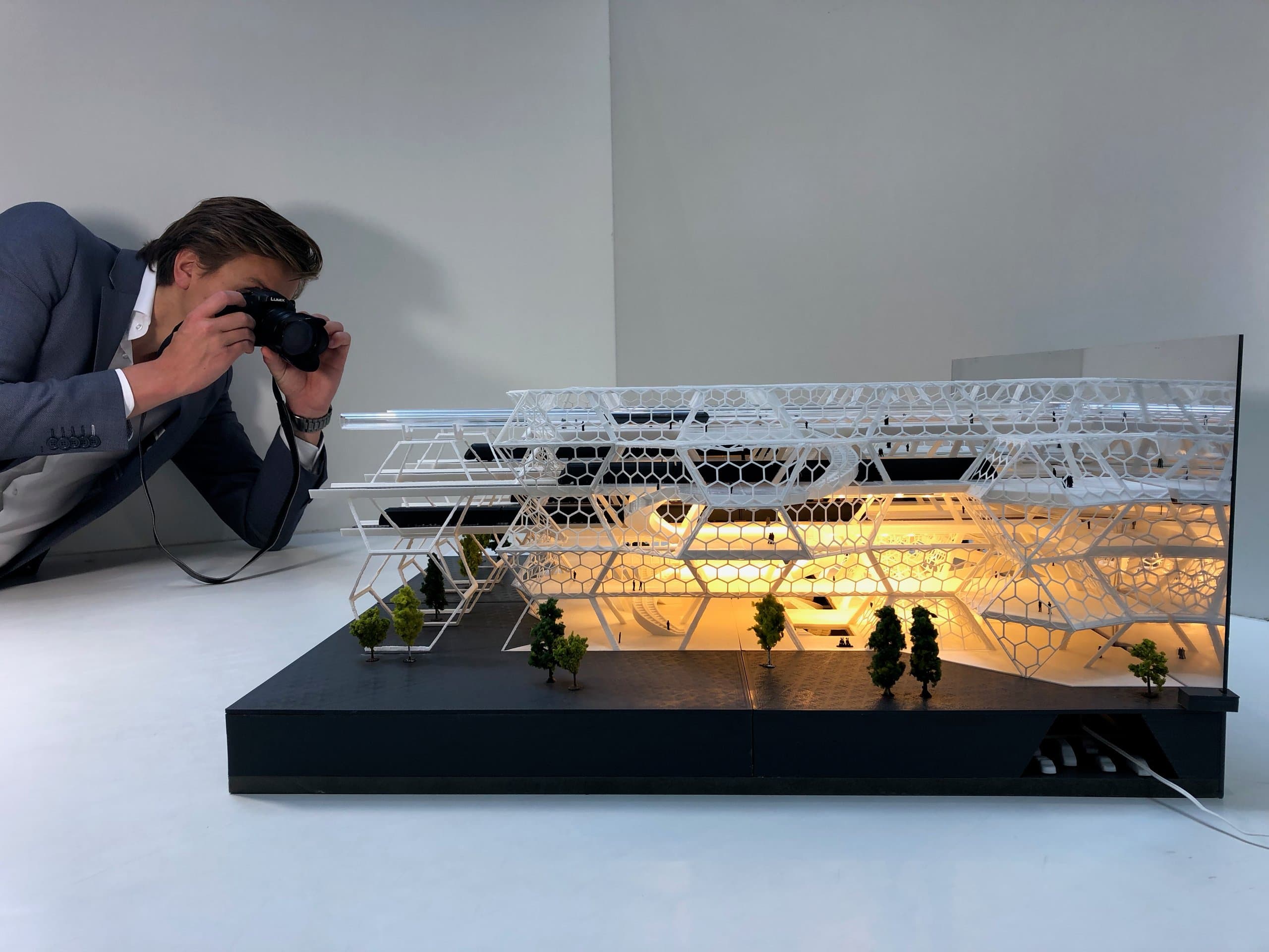 Fotograaf gehurkt achter de camera voor het verlichte schaalmodel van het station