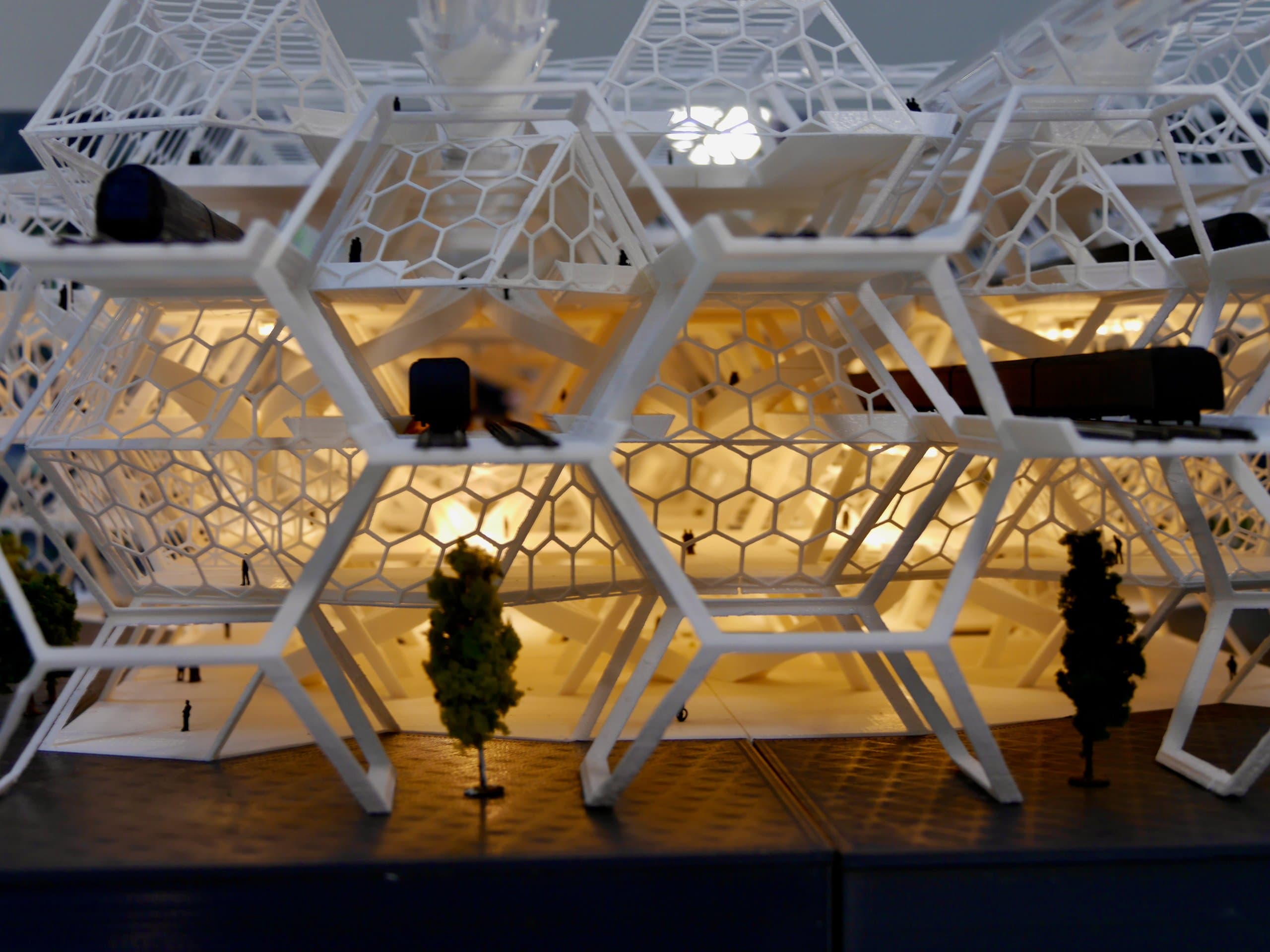 Close-up van de hexagonale gevel van het verlichte 3D-geprinte model, met boompjes op de voorgrond