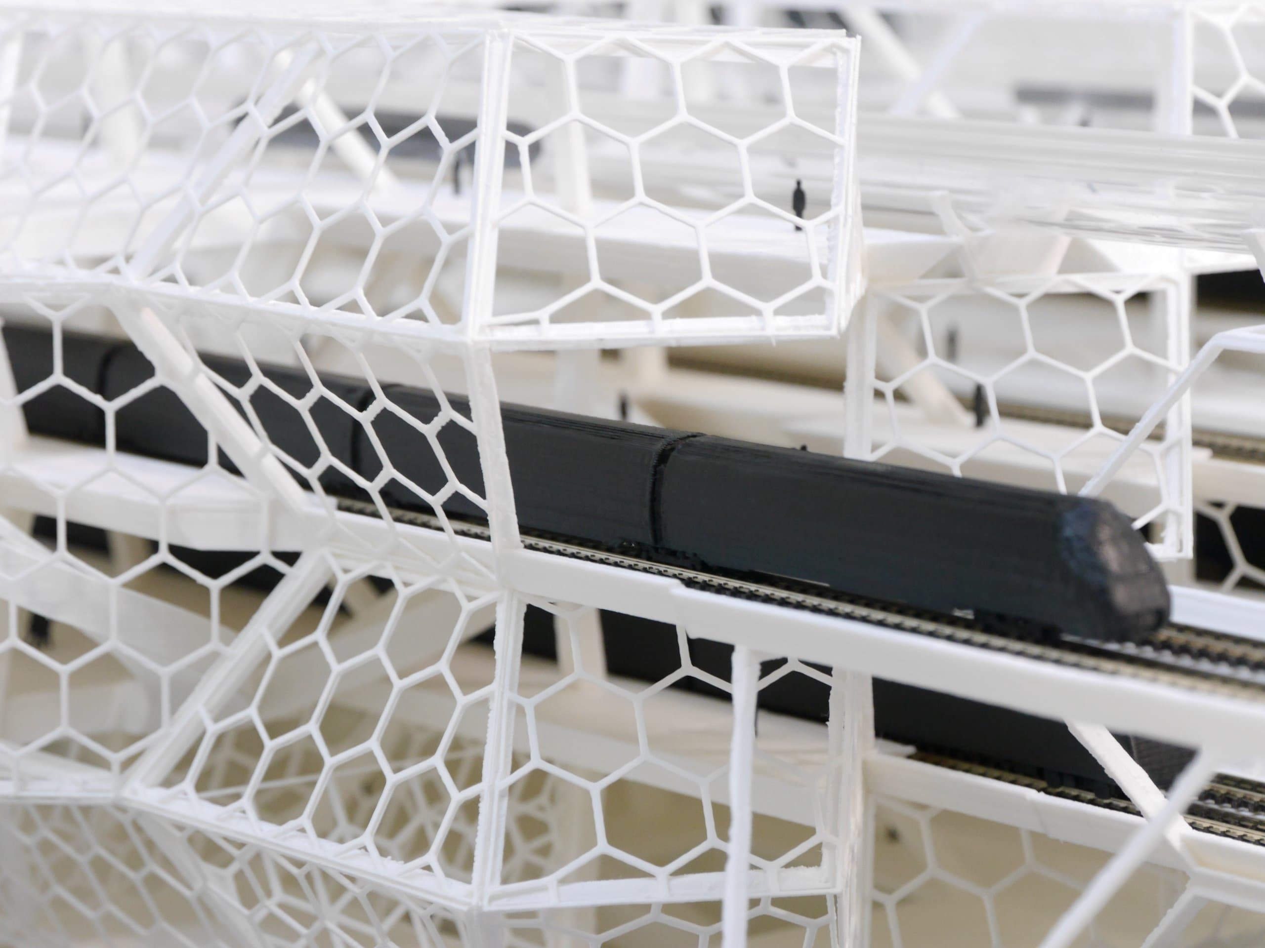 Detail van het schaalmodel met de zwarte trein tussen het witte hexagonale vakwerk