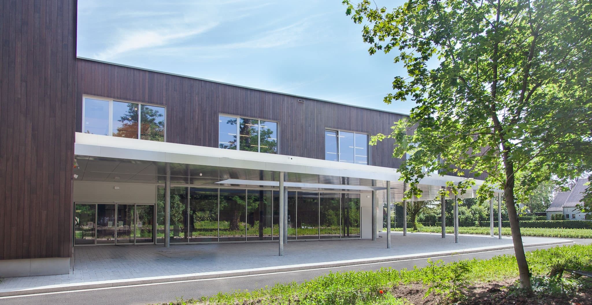 De entreezijde van het complex onder de luifel, met de bomen van het Stadspark ervoor
